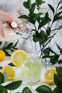 Person pouring lemon juice into a glass with ice