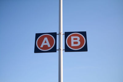 Low angle view of road sign against blue sky