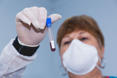 Close-up of doctor wearing flu mask holding blood sample