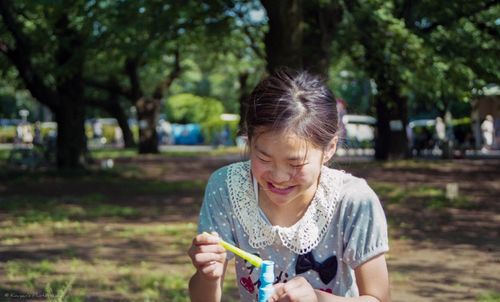 Portrait of young woman holding tree trunk