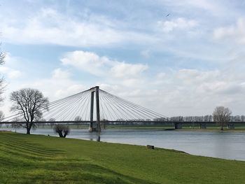 Bridge over river against cloudy sky