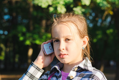 Serious girl talking on a dump phone in a summer sunny park