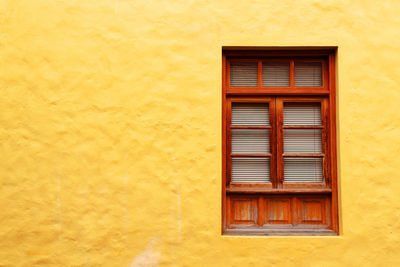 Close-up of window on yellow wall