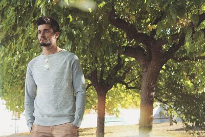 Young man standing against trees at park