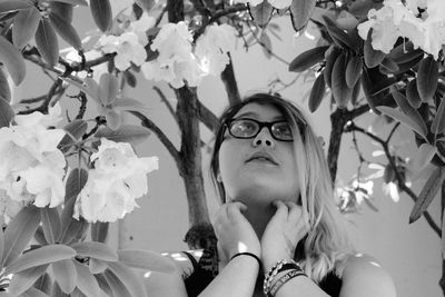 Young woman looking up while standing under flowering tree