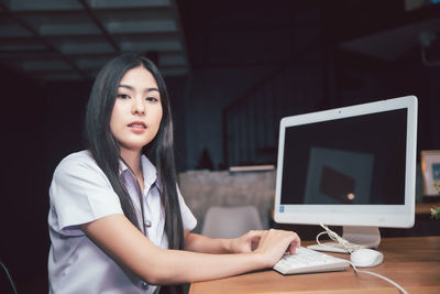 Young woman using mobile phone at table