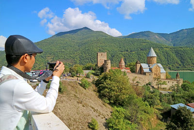 Visitor shooting pictures of ananuri medieval castle, famius landmark on aragvi river bank, georgia