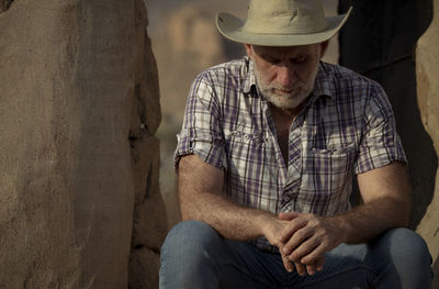 Adult man in cowboy hat and shirt sitting on step