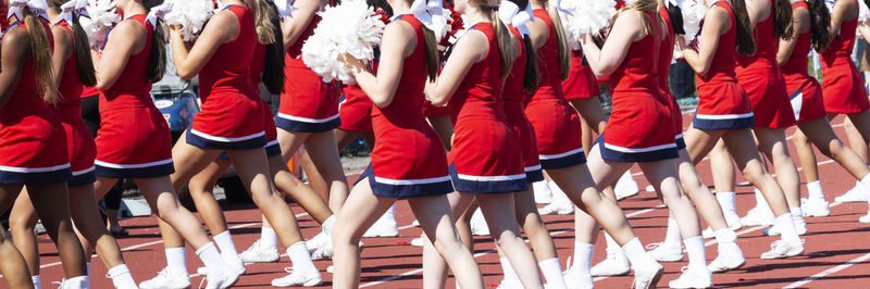 High school cheerleaders cheering while holding pom poms during a homecoming football game.