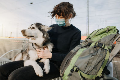 Woman wearing mask sitting with dog outdoors