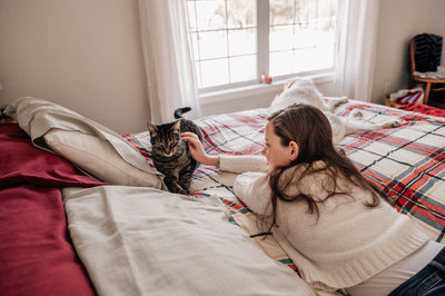 Girl petting her cat in bedroom