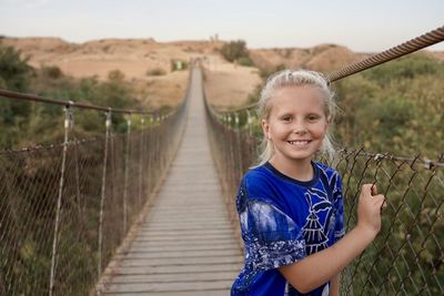 Portrait of smiling girl standing on footbridge