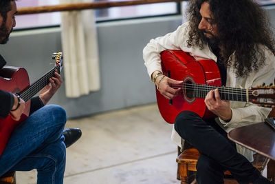 From above male friends playing guitars at table in music studio