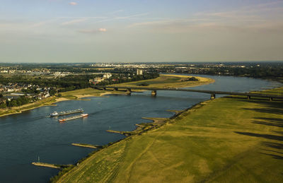 Aerial view of city by sea against sky