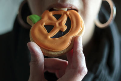 Woman eating halloween pumpkin cookie