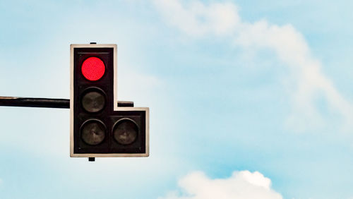 Low angle view of illuminated stoplight against sky