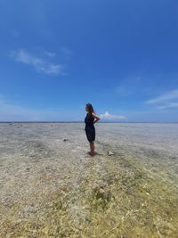 Woman standing on beach against sky