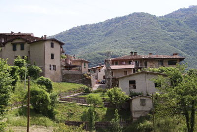 Houses by trees and mountains against sky