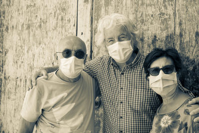 Portrait of smiling senior people standing by wooden wall outdoors