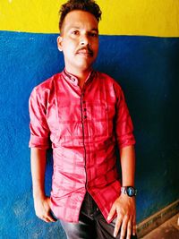 Portrait of young man standing against wall