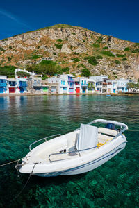 Sailboats moored on sea by buildings against sky