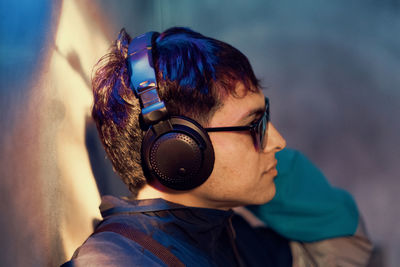 Young man listening to music against wall