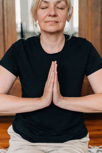 Midsection of mature woman meditating at home