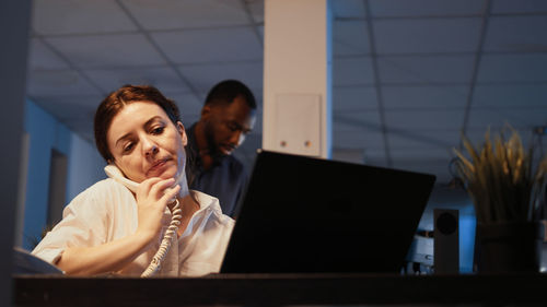 Young woman using mobile phone while sitting on table