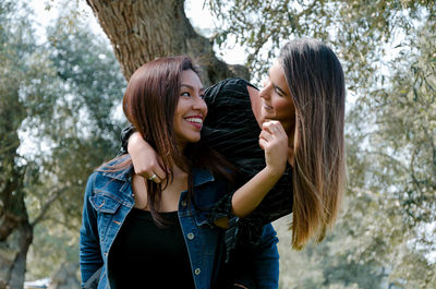 Young woman smiling while standing against trees