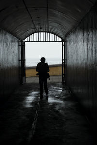 Rear view of silhouette man standing in tunnel