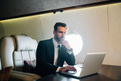 Businessman using laptop in airplane