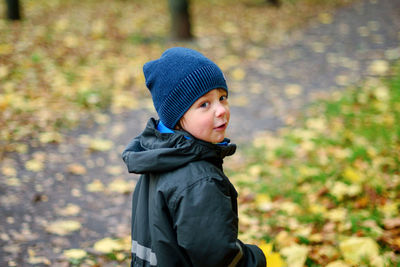 Cute little boy walking in the park on an autumn day. bad mood