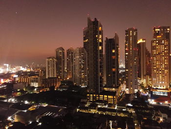 Illuminated buildings in city against sky at night