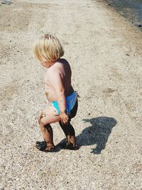 High angle view of shirtless boy lying on land