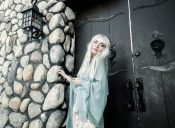 Woman standing by stone wall