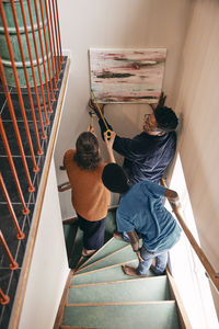 High angle view of family assisting each other while hanging painting on wall at home