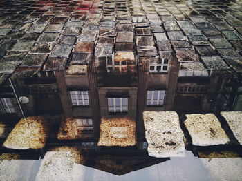 Reflection of building in puddle on cobblestone