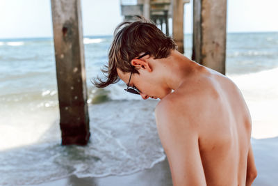 Midsection of shirtless boy at beach