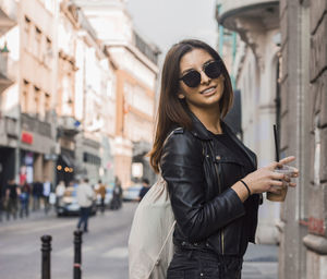 Portrait of smiling young woman standing in city