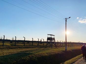 Electricity pylon on field against sky during sunset