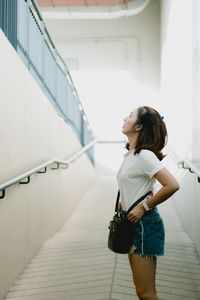 Side view of young woman looking up while standing on steps