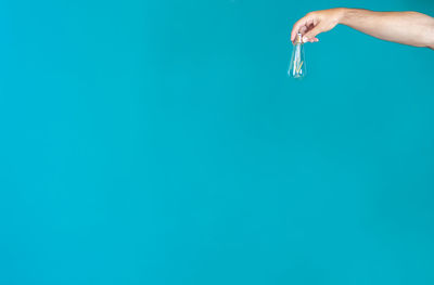 Close-up of hand holding paper against blue background