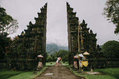 Couple on footpath at gate against sky