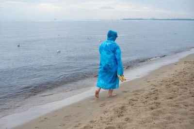 Woman in raincoat walking at beach