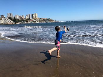 Full length rear view of woman walking on beach