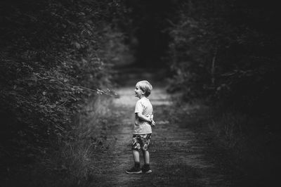 Side view of boy standing on field by plants