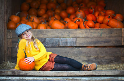 Portrait of a smiling young woman sitting by pumpkin