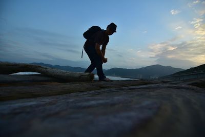 Low angle view of silhouette hiker bending against sky during sunset