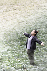 High angle view of woman standing with arms outstretched on agricultural field