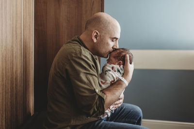 Side view of happy father kissing newborn boy in hospital